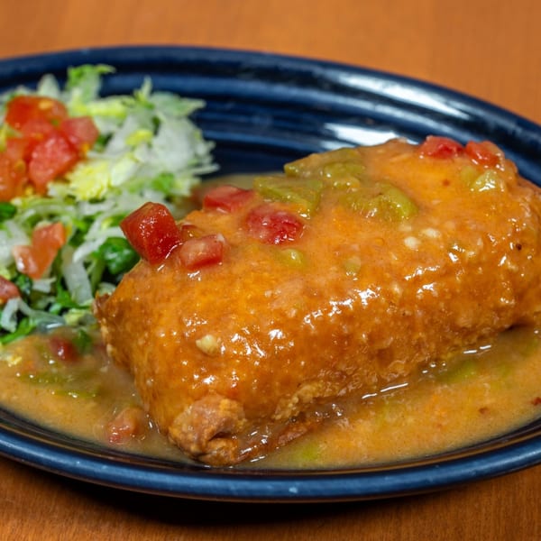 Mi Cocina's chimichanga covered in orange sauce with diced tomatoes and green peppers, served with lettuce.