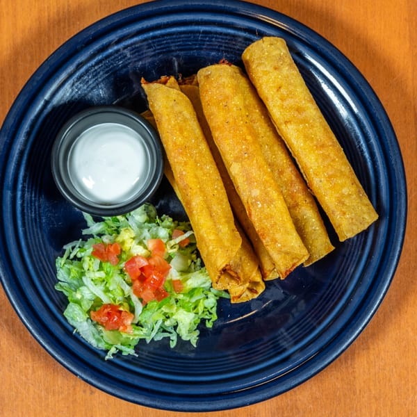 Mi Cocina's golden-fried flautas with shredded lettuce, diced tomatoes, and a side of sour cream.