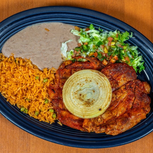 Mi Cocina's Mexican dish with grilled meat, rice, refried beans, salad, and a grilled onion slice.